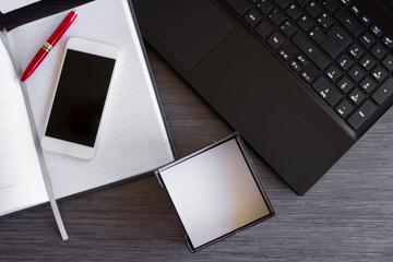 Smartphone, Laptop und Büromaterial auf einem hellgrauen Schreibtisch in einem modernen Büro