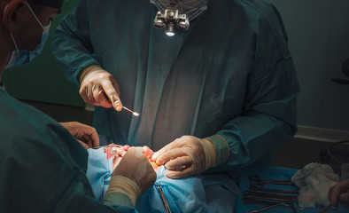 Surgeon and his assistant performing cosmetic surgery on nose