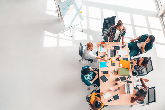 Multiethnic Diverse Group Of Business Coworkers In Team Meeting Discussion, Top View Modern Office With Copy Space. Partnership Professional Teamwork, Startup Company, Or Project Brainstorm Concept