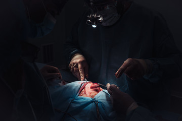 Surgeon and his assistant performing cosmetic surgery on nose