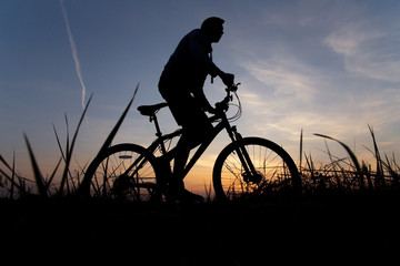 Fototapeta na wymiar Man, silhouette of a cyclist riding on mountain bike against the sunset sky. Sport, fitness outdoor