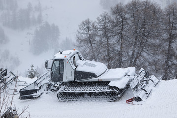 Snow grooming machines in heavy snowfall parked and ready for preparation of ski slopes. Winter ski...