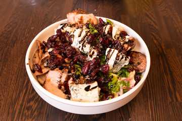 Plate with salad with duck, cheese and herbs on the serving table