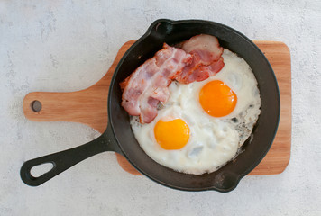 fried eggs with bacon in a pan top view