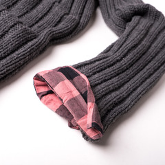 Gray wool sweater and checkered pink shirt on a white background.