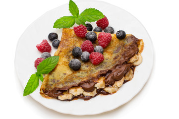 Homemade crepes served with chocolate cream, fresh blueberries and raspberries, powdered sugar on a white background