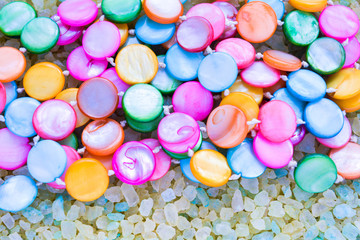 Fototapeta na wymiar Colorful Pearl Beads on Crystals of Aromatic Bath Sea Salt for Spa