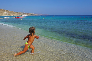 A three and a half years old girl playing small shells in the sea at Kalafatis Beach in Mykonos