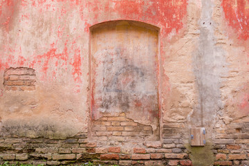 Old weathered painted wall background texture. Red dirty peeled plaster wall with falling off flakes of paint.
