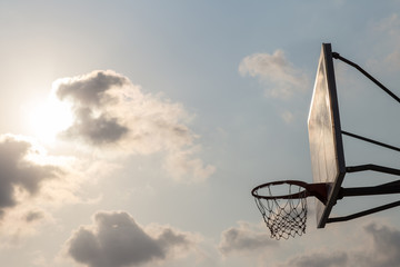 basket ball board under sky with white clouds. Basketball court with old backboard. sky and white clouds on background. Old basket ball Stadium.  basketball hoop in sky background on evening.