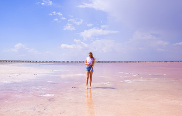 Girl in shorts and t-shirt on the pink salty lake 