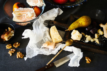 Still life on dinner table with cheese, pear, wine, walnut, pomelo on wooden board.