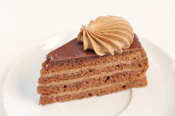A piece of delicious chocolate birthday layer cake dessert with chocolate cream decoration on a white plate meny style