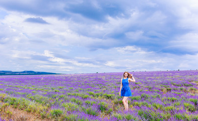 Girl in blue dress on lavender field in cloudy weather