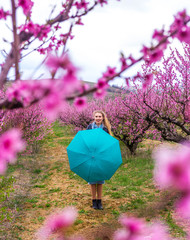 The girl with the turquoise umbrella in the peach garden. 