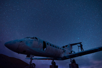 Old airplane at the starry night.  man standing on the plane wing.
