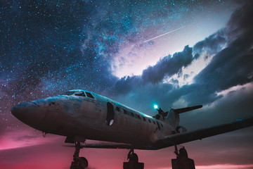 Old airplane at the moon night. Man sitting on the top of old plane.	