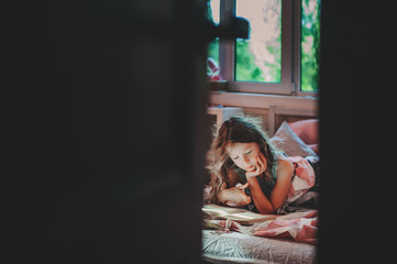 thoughtful kid girl reading book alone in her room in the veening or early morning