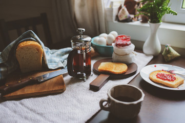 country cottage kitchen with breakfast on wooden table. Toast with jam, farm eggs and coffee