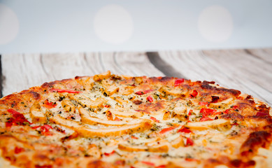 Pizza on a wooden background. Pizza with chicken and cheese on a white background. The concept of eating pizza, preparing a quick dish for guests.