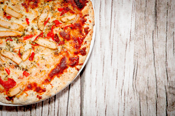 Pizza on a wooden background. Pizza with chicken and cheese on a white background. The concept of eating pizza, preparing a quick dish for guests.