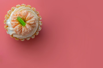 Cupcake with a cap air of cream  on a pink background.