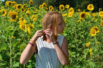 Mädchen von der Seite, bindet ihre Haare in einem Sonnenblumen Feld