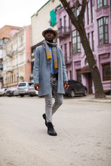 African american man in coat and hat walking along city street