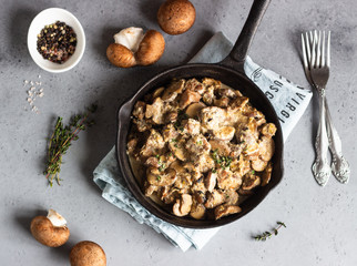 Meat stewed with mushroom and thyme in a cast-iron pan.  Grey concrete background. Copy space. 
