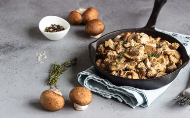 Meat stewed with mushroom and thyme in a cast-iron pan.  Grey concrete background. Copy space. 