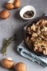 Meat stewed with mushroom and thyme in a cast-iron pan.  Grey concrete background. Copy space. 