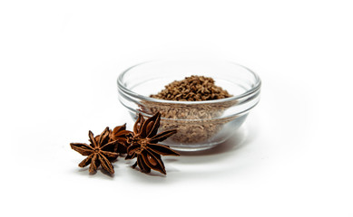 Grains of anise and anise stars in a bowl on a white background. Anise put on the table. The concept of using seasonings for dishes. Eating spiced dishes.