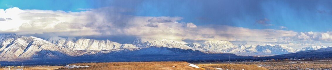 Fototapeta na wymiar Winter Panoramic view of Snow capped Wasatch Front Rocky Mountains, Great Salt Lake Valley and Cloudscape from the Bacchus Highway. Utah, USA.