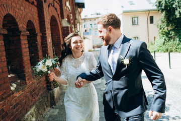 A beautiful wedding couple in the retro style sincerely have fun. Happy bride and groom have fun running together and looking at each other