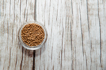 Coriander seeds on a wooden table in a bowl. Coriander placed on the table. The concept of using seasonings for dishes. Eating spiced dishes.