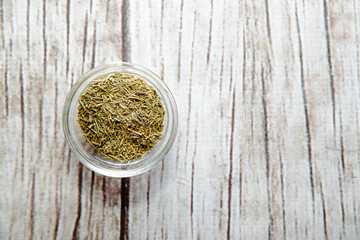 Fototapeta na wymiar Dried rosemary on a wooden background in a bowl. Rosemary placed on the table. The concept of using seasonings for dishes. Eating spiced dishes.