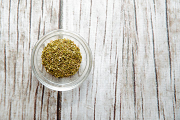 Dried oregano on a wooden background in a bowl. Oregano located on the table. The concept of using seasonings for dishes. Eating spiced dishes.