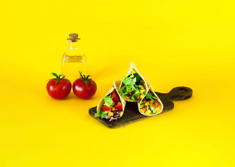 Traditional dish of Mexican cuisine. Corn tortilla tacos with vegetable filling on yellow background.