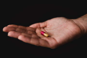Medicine pills in hand, isolated on black background. Pharmacy and medication.