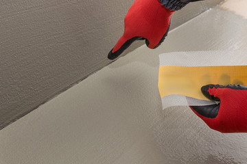 worker holds sealing tape for gaps, a connection between the vertical and the horizontal part