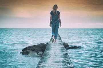 Rolgordijnen Lonely woman walking on the concrete pier at the sea.  © robsonphoto