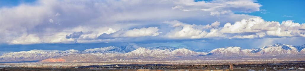 Winter Panoramic view of Snow capped Wasatch Front Rocky Mountains, Great Salt Lake Valley and Cloudscape from the Bacchus Highway. Utah, USA.