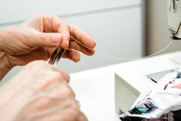 Sewing on a sewing machine. Woman uses a sewing machine to sew clothes, decorations from material. Fashion and beauty concept, sewing clothes. A woman works at home, passion.