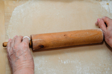 Rolling pasta dough. The woman uses a rolling pin to prepare the homemade pasta. The concept of...