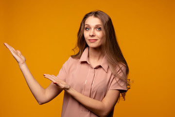 Photo of glad woman pointing at something over the yellow backgrownd