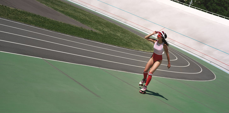 Freedom. Beautiful woman is rollerblading on the stadium, smiling and looking at camera