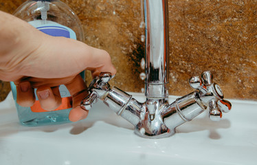 Unscrewing tap water. The man unscrews the water faucet to wash his hands, taking care of personal hygiene. The problem of hand-borne diseases, flu, abdominal pain.