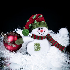 fun toy snowman and Christmas ball on a black background.