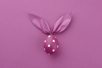 Purple dotted Easter egg with paper bunny ears, holiday concept