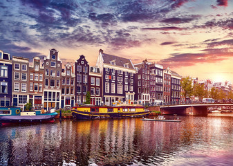 Amsterdam, Netherlands. Floating Houses and houseboats and boats at channels by banks. Traditional dutch dancing houses among trees. Evening autumn street above water pink sunset sky with clouds. - obrazy, fototapety, plakaty